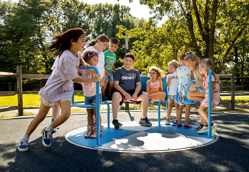 Kids playing on inclusive whirl commercial playground equipment
